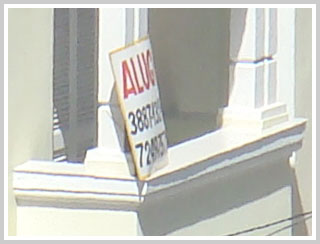 Detalhe de varanda com placa Aluga-se: vista parcial de número de telefone